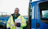 Image of a contractor standing outside his truck wearing a safety vest.